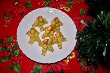 Plat de pommes-frites découpées en forme de sapins de Noël sur nappe de fête
