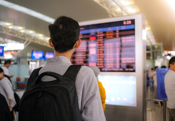 A man with backpacker looking for information on electronic information board and departure board in airport. Royalty stock image of tourist in terminal departure find for information on departure