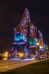 Illuminated old port cranes on a boulevard in Szczecin City at night © Mike Mareen
