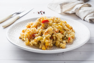 Pilaf with vegetables and chicken in a gray plate on a light background.