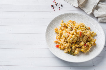 Pilaf with vegetables and chicken in a gray plate on a light background. Copy space
