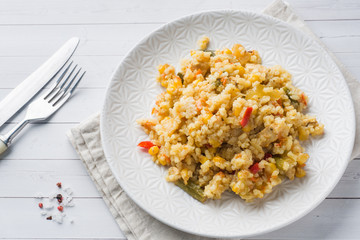 Pilaf with vegetables and chicken in a gray plate on a light background.
