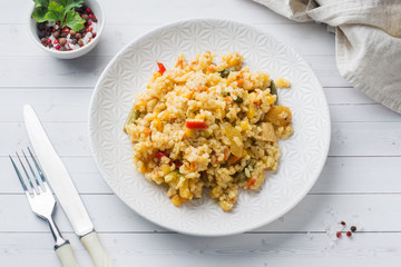 Pilaf with vegetables and chicken in a gray plate on a light background.