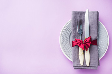 Cutlery, plates knife and fork with napkin on pink background. Holiday table concept