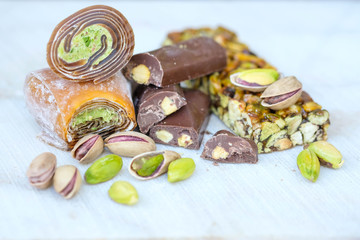 Eastern Turkish sweets with pistachios on a white wooden background. Fragrant baklava, chocolate, sweets with pistachios.