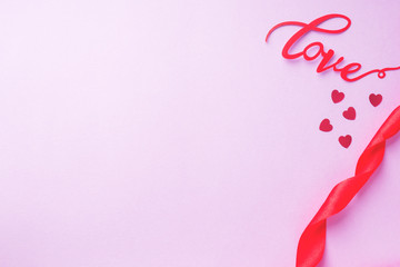 concept Valentine's day, Red ribbon and the inscription love on a pink background.