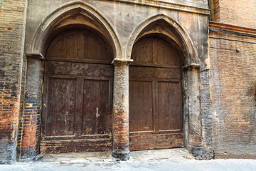 Fototapeta na wymiar Wooden arch door on medieval brick building in Siena. Italy