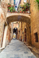 Medieval narrow street Vicolo Delle Scotte in Siena, Tuscany, Italy.
