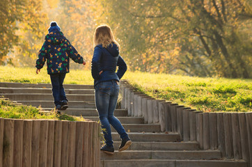 Mom walks with her son in the Park in autumn. Mother makes sure he doesn't fall
