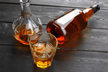 bottle and glass of whiskey on a wooden background