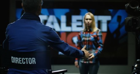 Medium shot of young woman singing at talent show director shows her thumbs up and says she is accepted