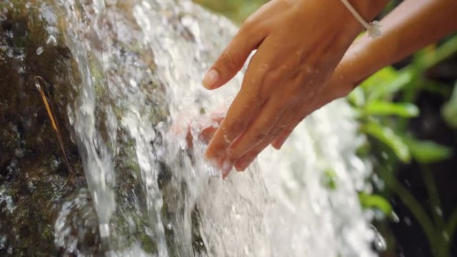 Female Hand Touching Fresh Clean Natural Spring Waterfall in Jungle Rainforest. 4K Slowmotion. Bali, Indonesia.