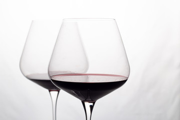 two glass glasses with red wine on a white background close-up.