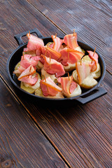 baked bacon with potatoes in a cast iron skillet