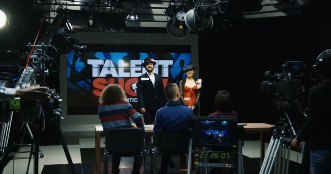 Wide shot of a duo introducing themselves in front of jury at a talent show