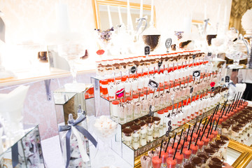 Delicious and tasty dessert table with cupcakes shots at reception closeup