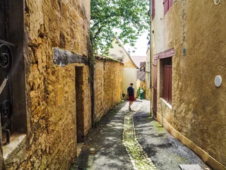 Fotobehang Smal steegje Young man walking in a narrow alley in the city center of the medieval village of Gourdon in Lot, France  © Luoxi