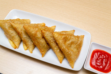 Spring rolls served with sauce on wooden table