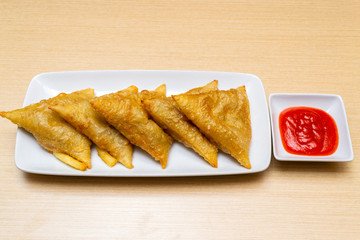 Spring rolls served with sauce on wooden table