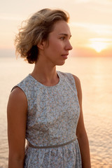Natural portrait of a blonde woman in a dress near the sea in profile