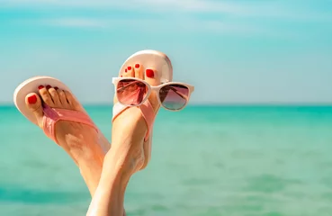 Wall murals Pedicure Upside woman feet and red pedicure wearing pink sandals, sunglasses at seaside. Funny and happy fashion young woman relax on vacation. Chill out girl at beach. Creative for tour agent. Weekend travel.