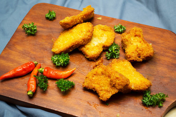 Chicken nuggets served on wooden chopped board with spatula