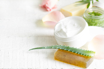 Natural cosmetics for skin care with petals rose and aloe vera on white planks
