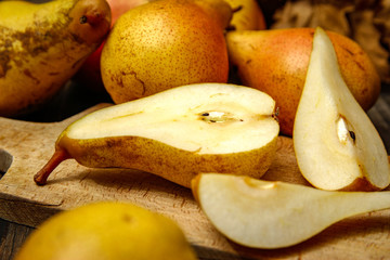 Fresh raw organic pears on old cutting board and rustic wooden table. Close-up.