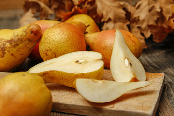 Fresh raw organic pears on old cutting board and rustic wooden table. Close-up.