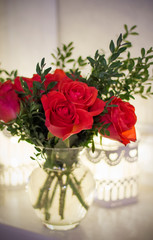A bouquet of red roses and boxwood in a vase with cells