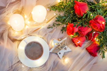 Fototapeta na wymiar Composition: red roses with boxwood, garlands, candles, star and cup coffee (tea)