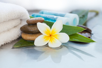 Fototapeta na wymiar Еropical flowers, bowl of water, towel and oil tube. Body care and spa concept