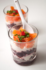 closeup of beet and salmon appetizers in little glasses on white background