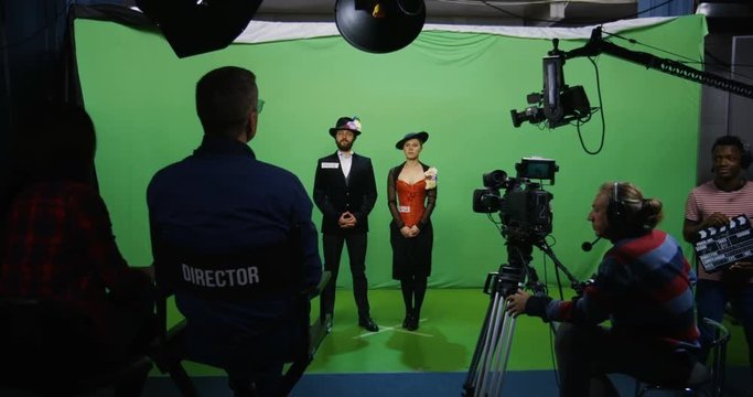 Slow motion wide shot of a cameraman recording an actor and an actress performing a romantic scene