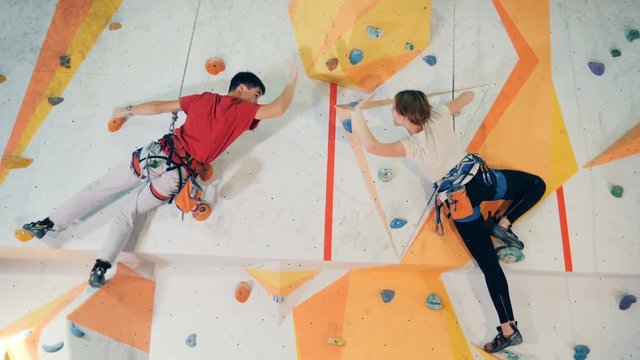 People give a five, greeting each other on a climbing wall, close up.