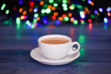 Enjoying coffee on christmas morning. Coffee time christmas eve. Fresh brewed coffee in white cup or mug on defocused garland lights background. Coffee drink winter holiday new year