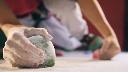 Person climbing on a wall, holding rocks, top view.