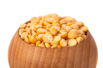 Dry yellow peas on wooden bowl isolated on white background