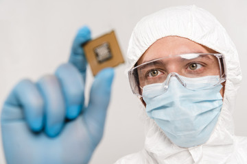 Fototapeta premium selective focus of scientist looking at microchip in latex glove isolated on grey
