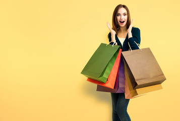 Beautiful woman with shopping bags, over yellow