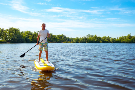 Happy man is paddling on a SUP board