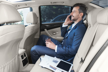 Businessman talking on smartphone and drinking coffee