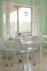 White table and chairs near the window in an empty cozy cafe.