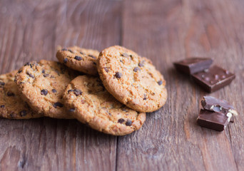 delicious, crispy oatmeal cookies with chocolate on wooden background