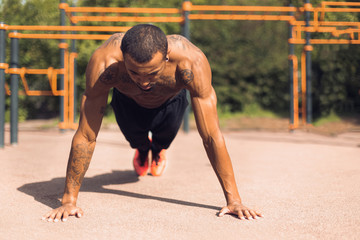 Fototapeta premium Shirtless man doing push ups on sports ground
