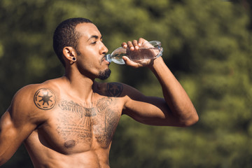 Athletic man drinking water after workout outdoors