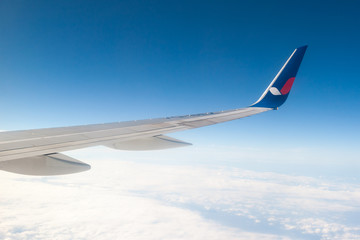 Wing aircraft against the blue sky and clouds.