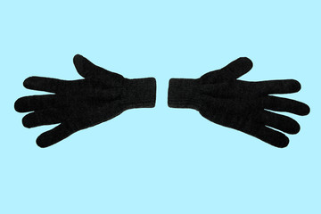 A pair of grey winter knitted gloves. Horizontally. On a blue background. The view from the top. Isolated.
