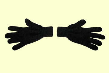 A pair of grey winter knitted gloves. Horizontally. On yellow background. The view from the top....