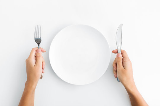 Whte plate with silver fork and knife on white background